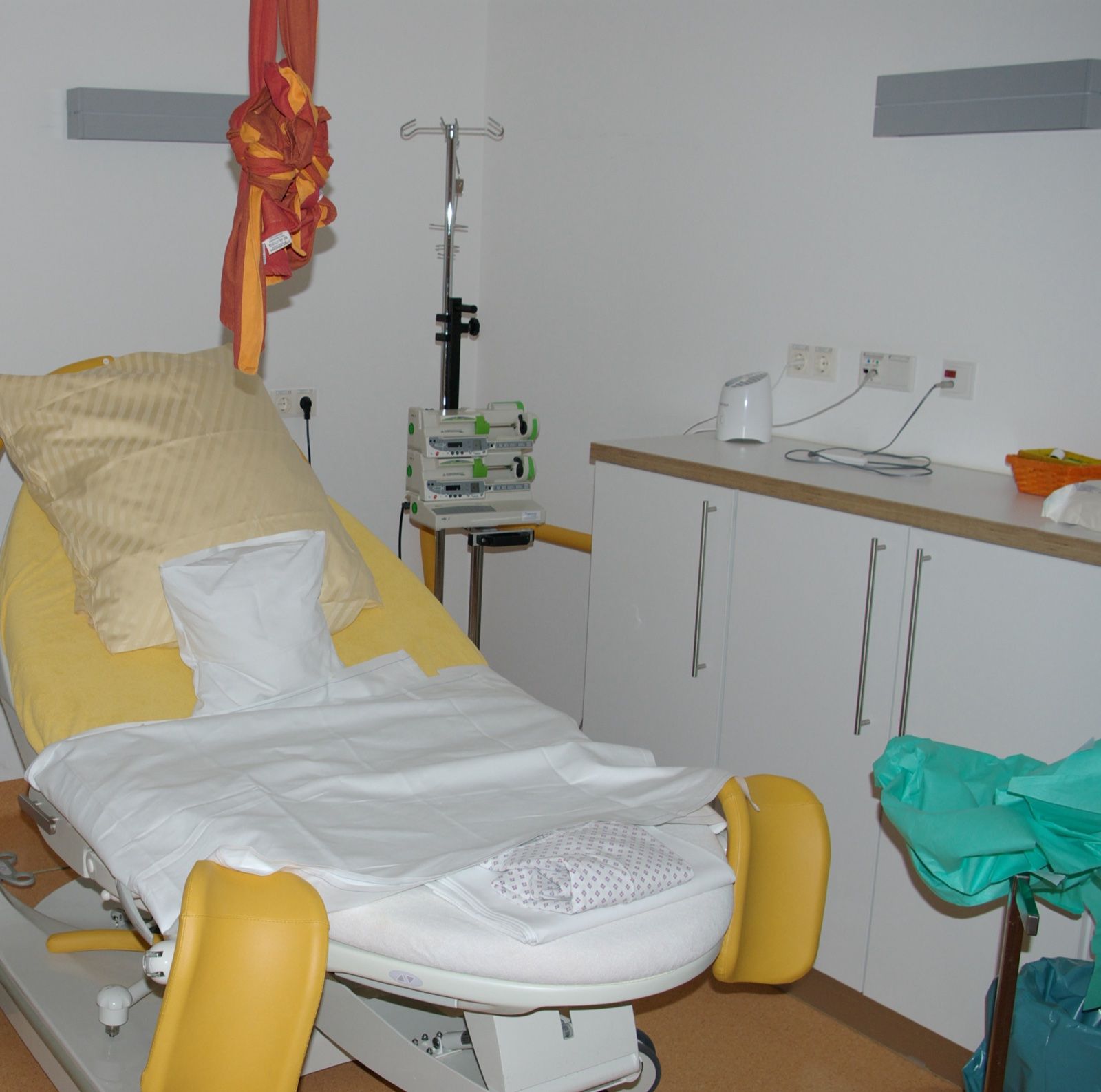 An empty delivery bed made up with fresh linens in a quiet birthing room, a Wikimedia Commons photograph in the encyclopedia of Candace Cooley