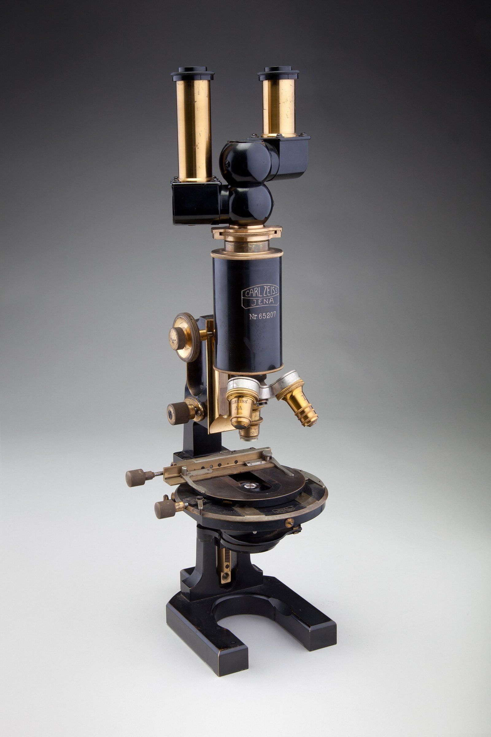 A brass and black binocular compound microscope made by Carl Zeiss Jena in 1914, a Wikimedia Commons photograph in the encyclopedia of Candace Cooley